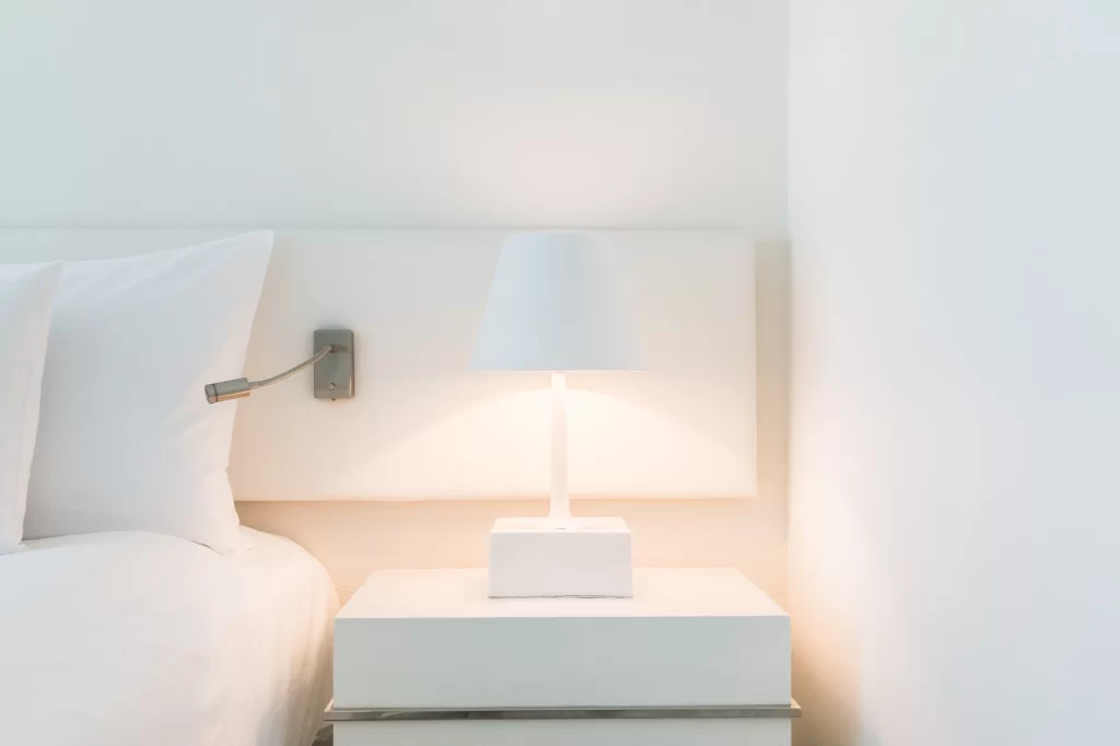 White nightstand with a lamp on it