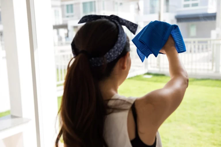 Portrait of a young woman with arms raised while cleaning a window in Denver, Colorado.