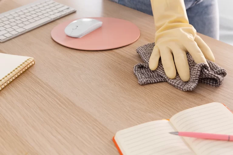 Someone in rubber gloves tidying up desk with computer accessories.