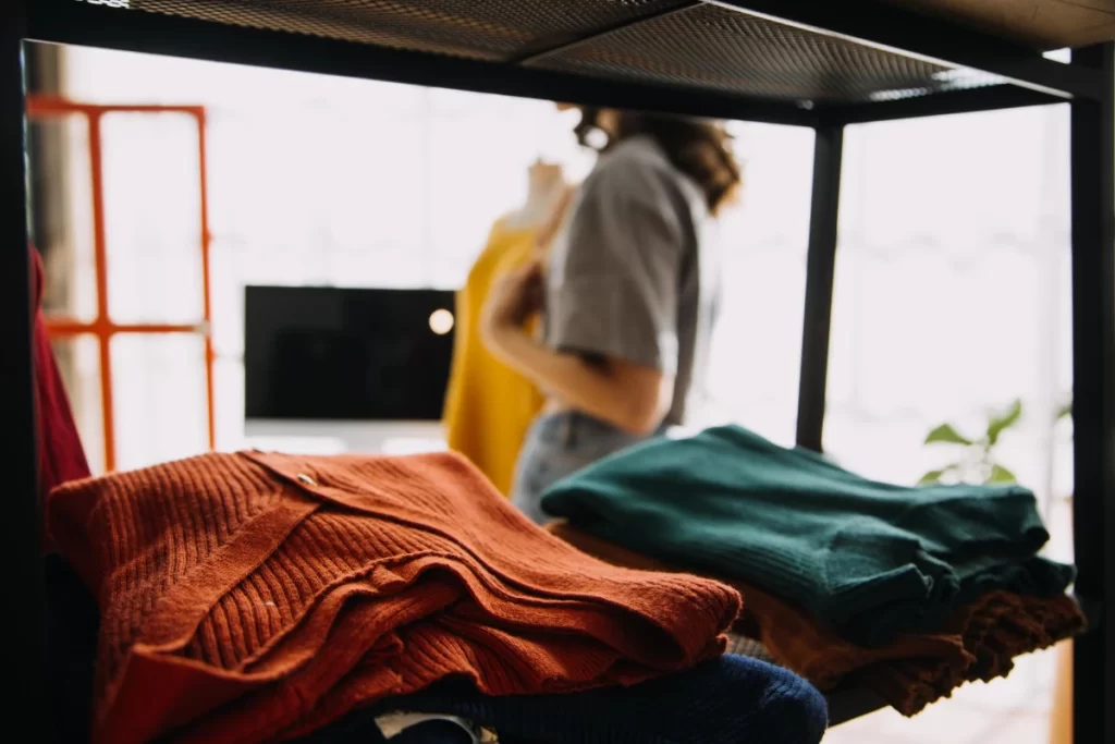 The young cleaning lady is folding clothes and putting them together.