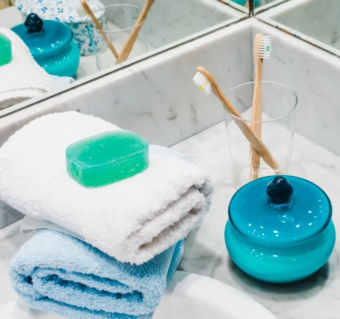 A bathroom counter with neatly arranged blue and white towels and toothbrushes.